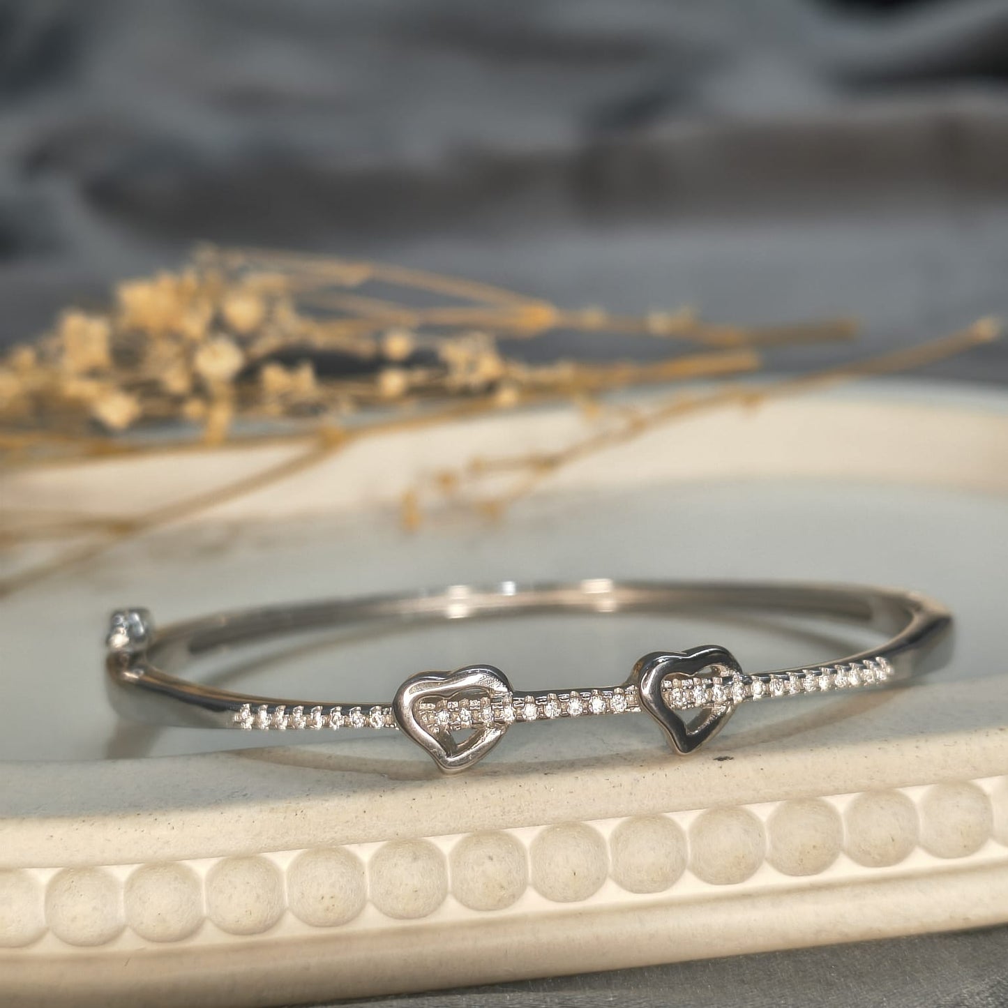 Silver bracelet with heart designs on a textured surface