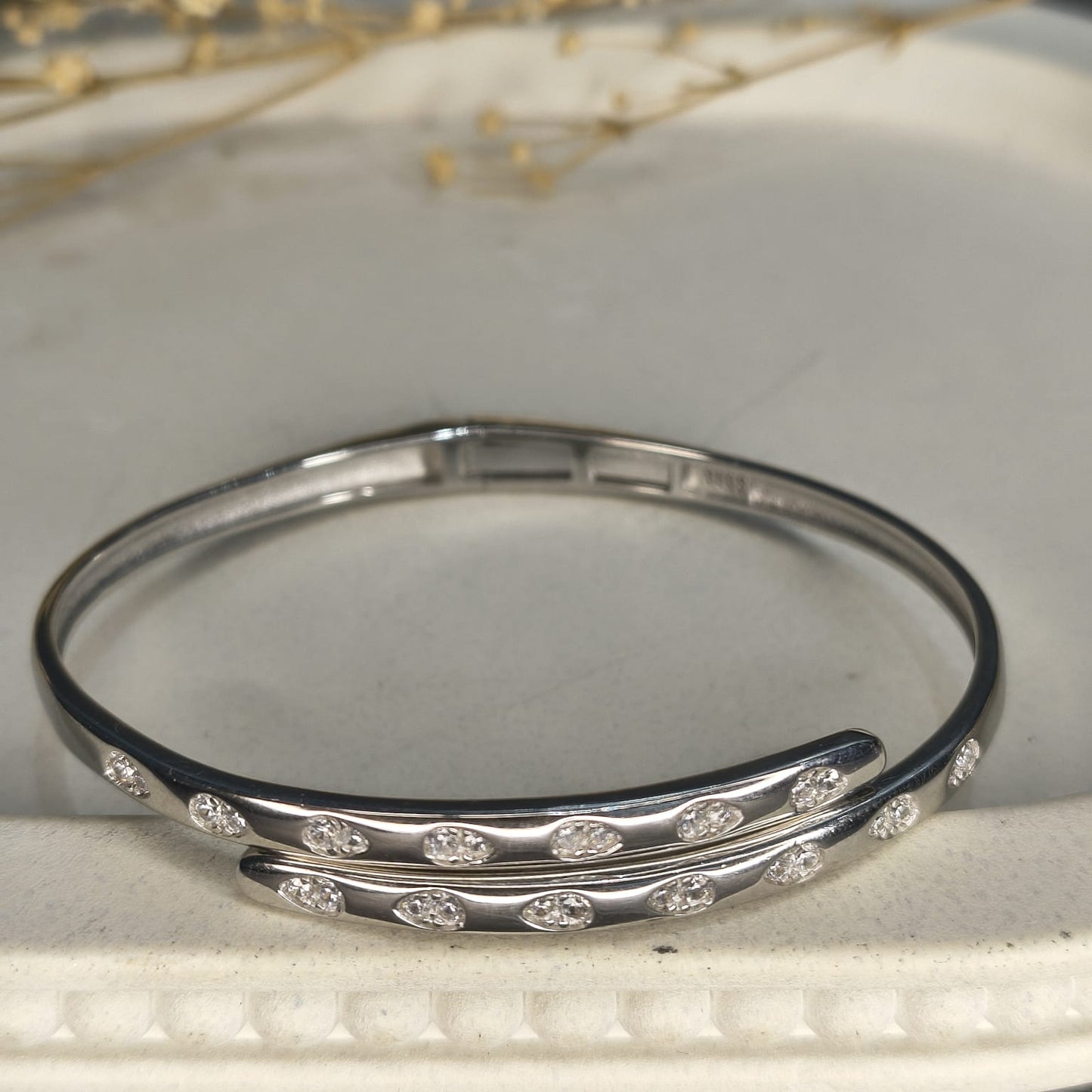 Silver bangle with embedded stones on a light background