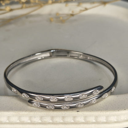 Silver bangle with embedded stones on a light background