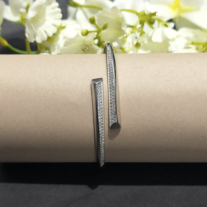 Silver bracelet on a cylindrical object with white flowers in the background