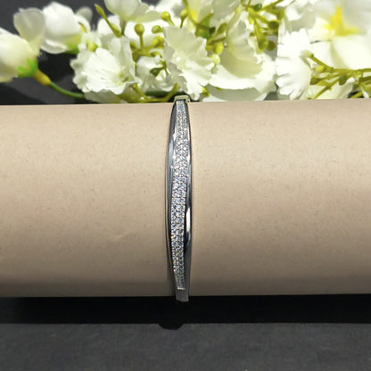 Silver bracelet on a cardboard roll with white flowers in the background