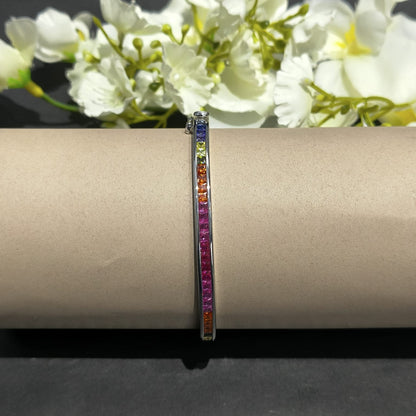 Multicolored gemstone bracelet on a beige surface with white flowers in the background
