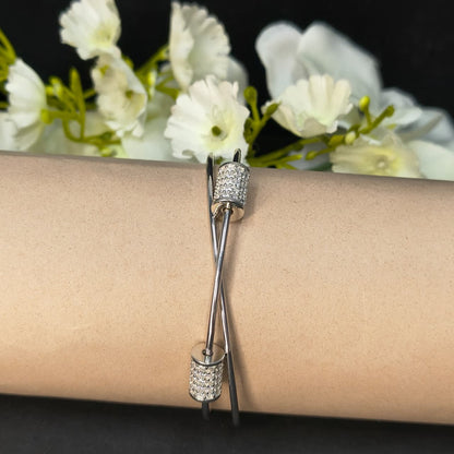 Silver bracelet on a wrist with white flowers in the background
