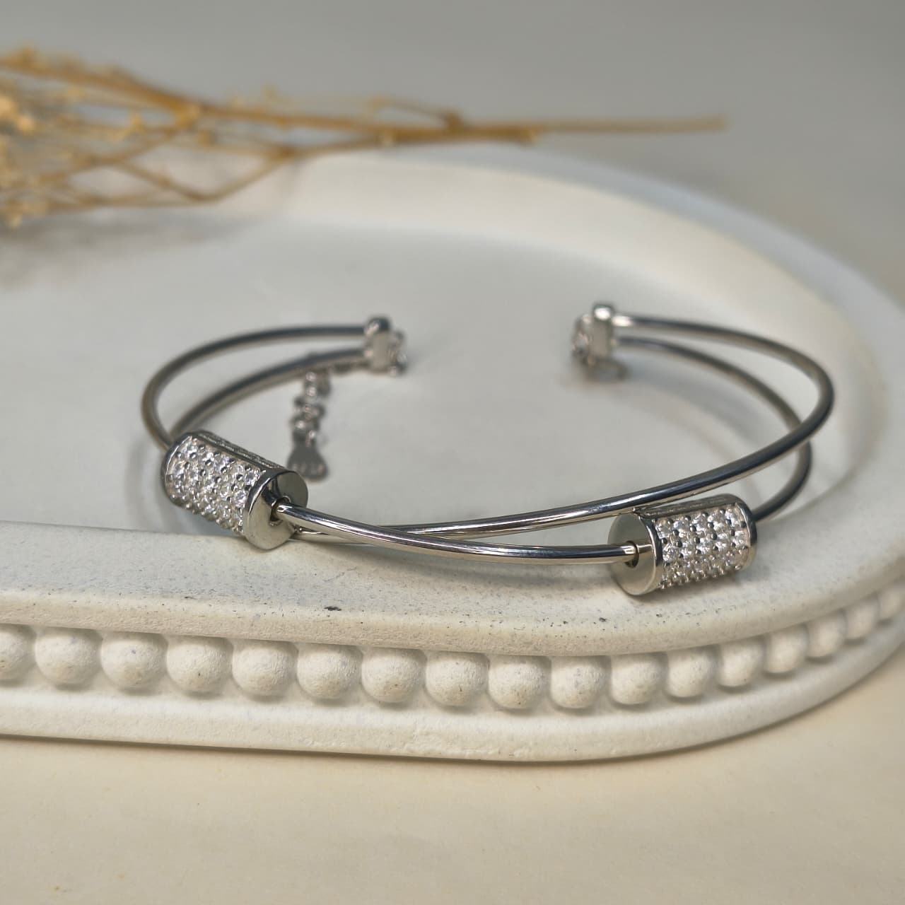 Silver bracelet with decorative beads on a white dish