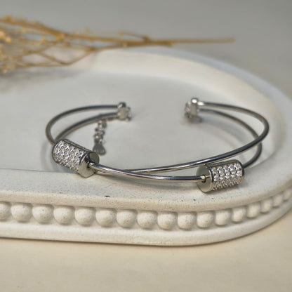 Silver bracelet with decorative beads on a white dish