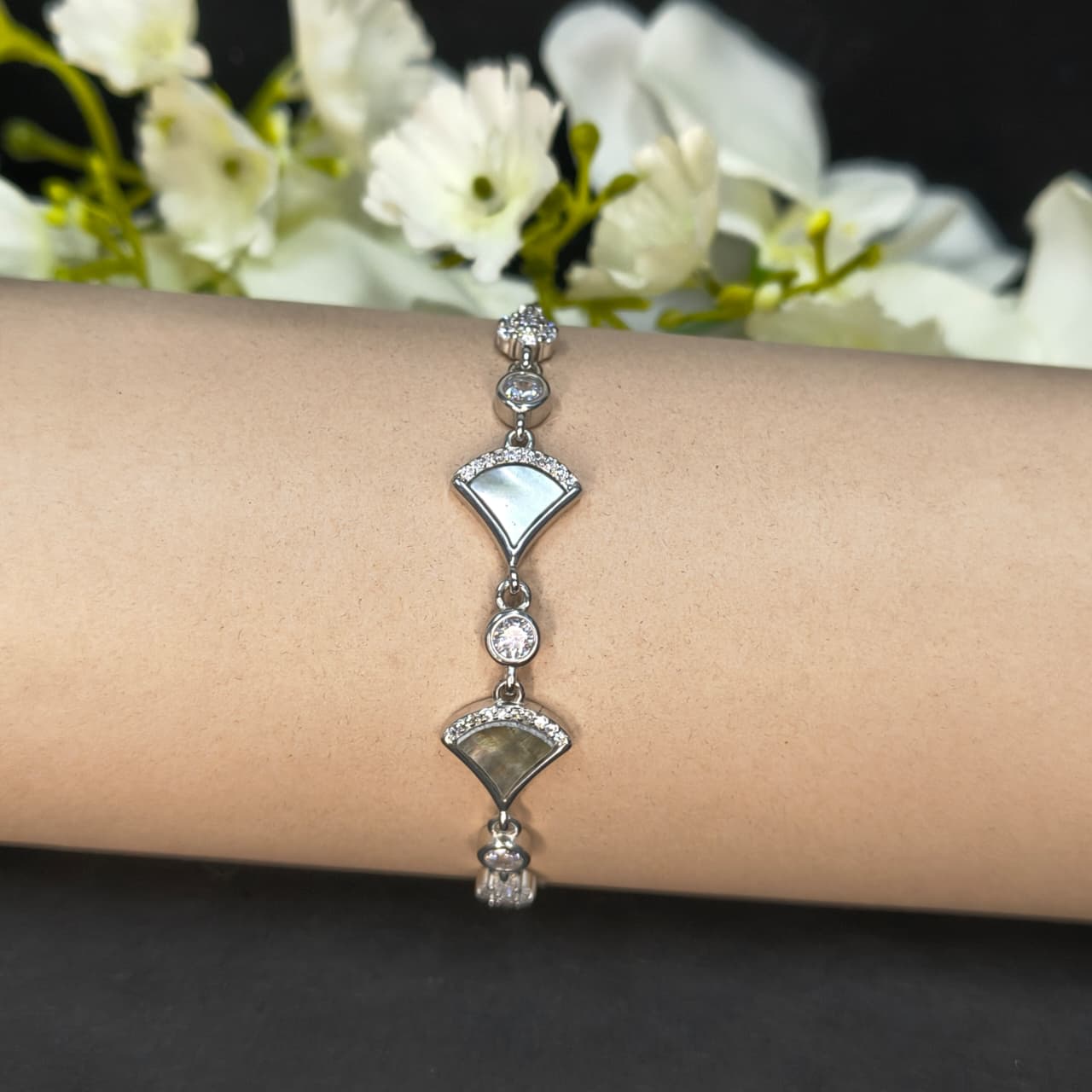 Silver bracelet on a wrist with a blurred floral background