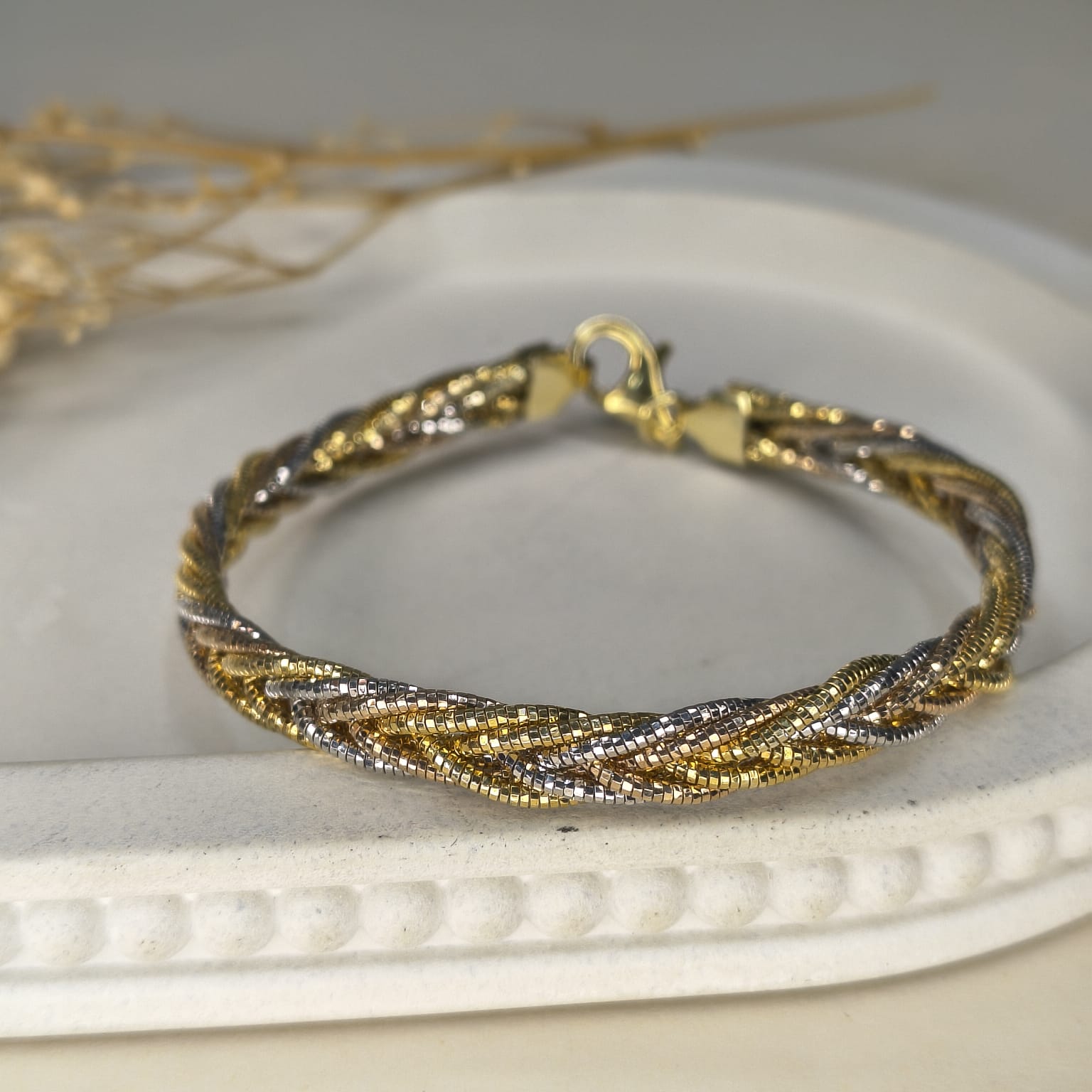 Gold and silver braided bracelet on a white surface