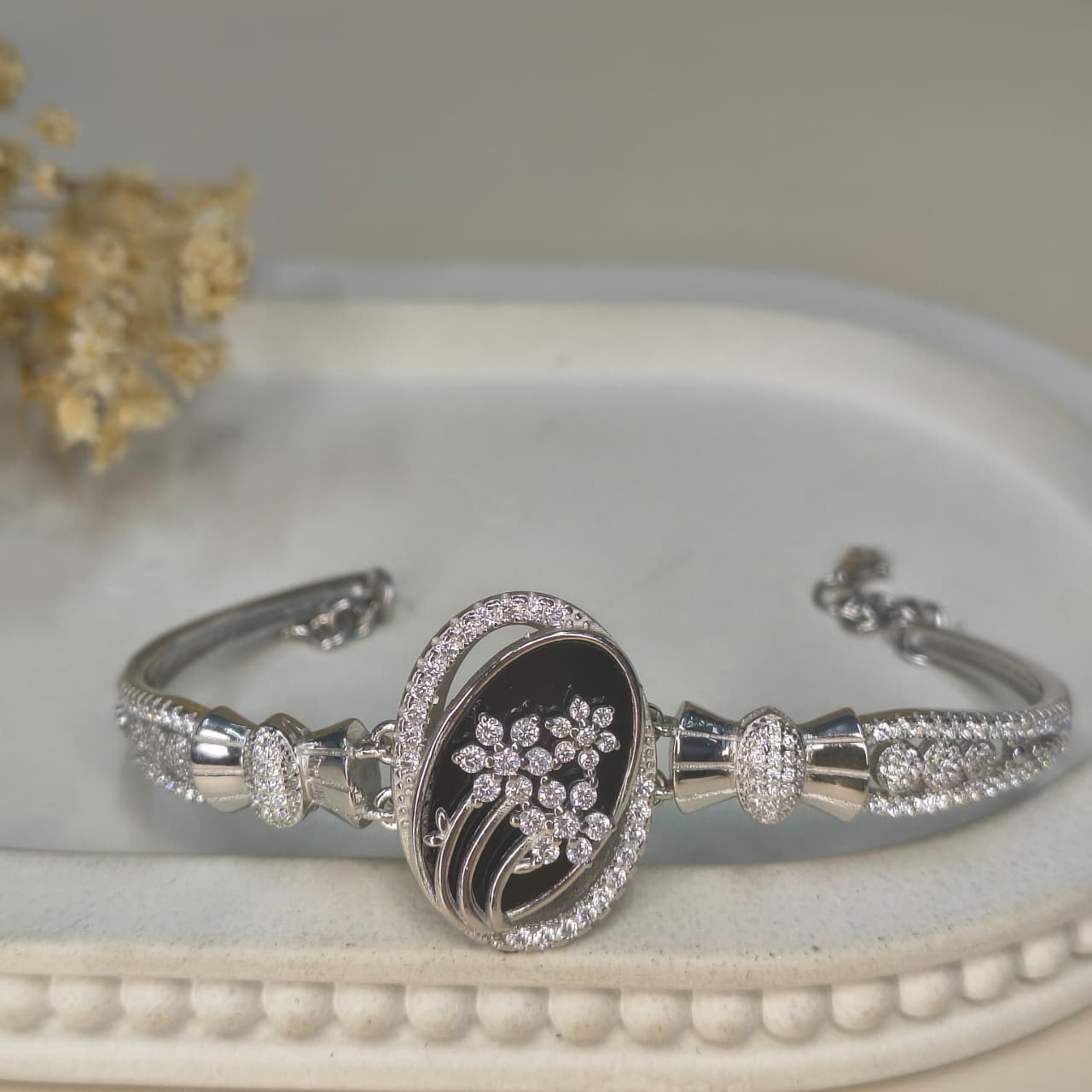 Silver bracelet with floral design on a white surface