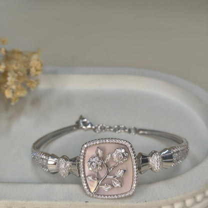 Silver bracelet with floral design on a white surface