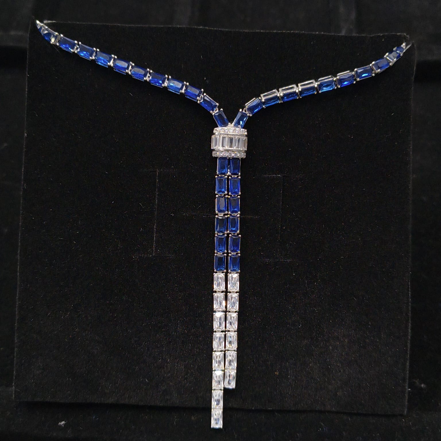 Necklace with blue and white gemstones on a black stand
