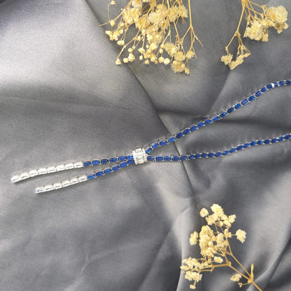 Blue and silver beaded necklace on a gray fabric background with dried flowers.