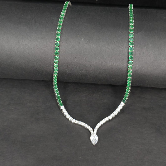 Necklace with green gemstones and a diamond pendant on a dark background