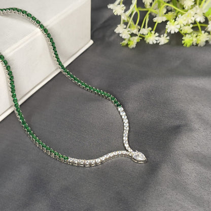 Emerald and diamond necklace on a gray surface with flowers in the background
