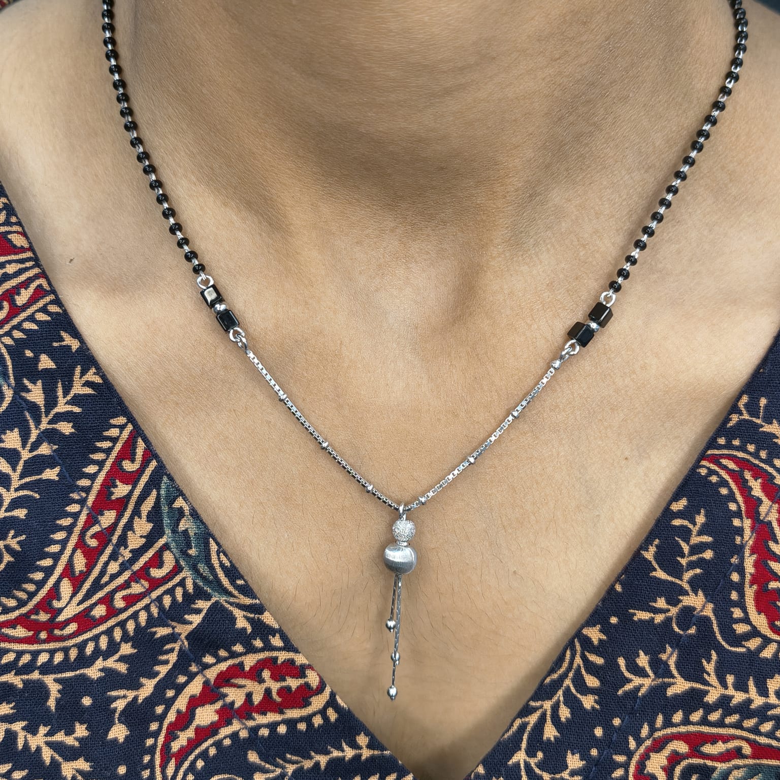 Necklace with a pendant on a person wearing a patterned garment