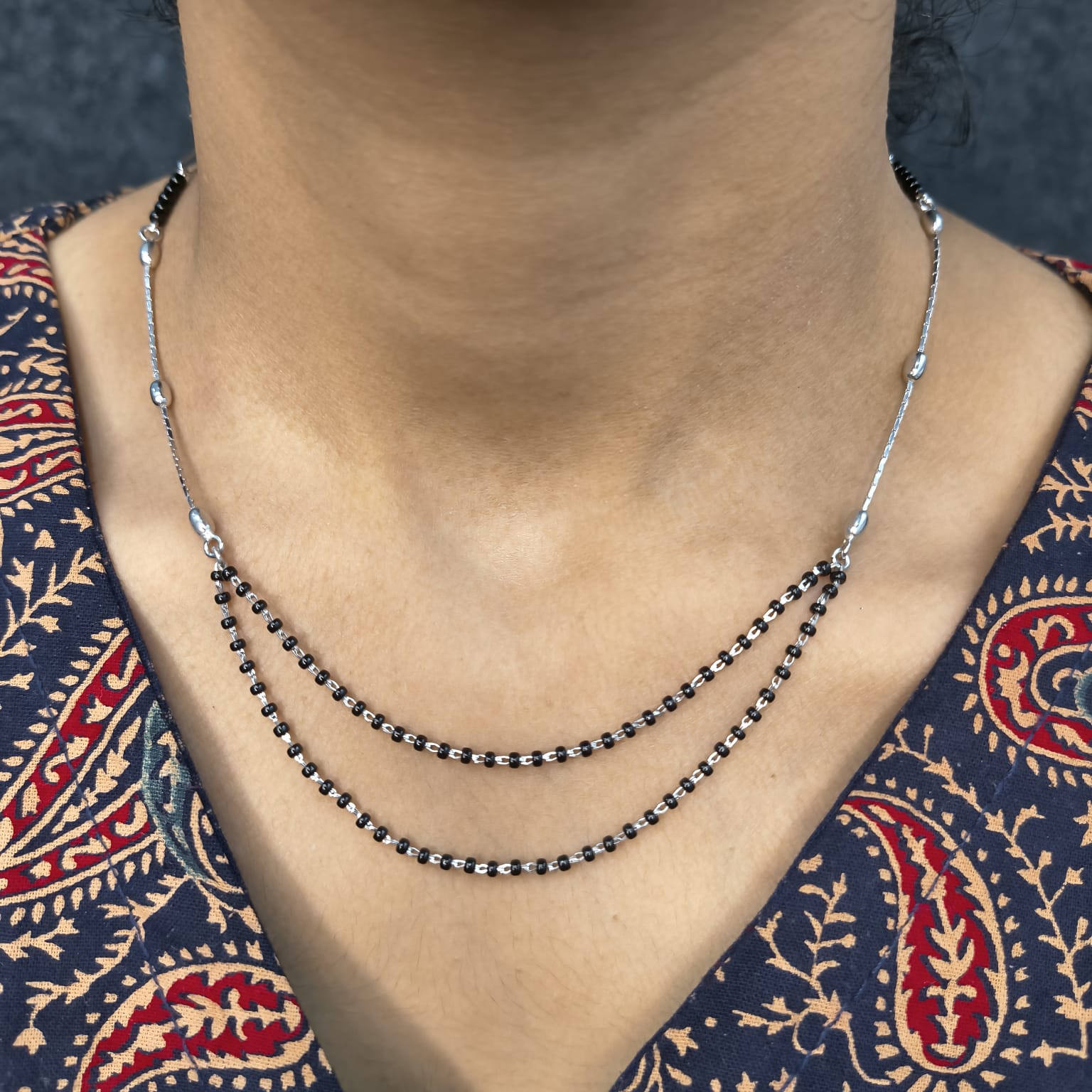 Necklace with black beads on a person wearing a patterned garment