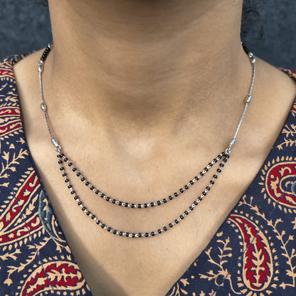 Necklace with black beads on a person wearing a patterned garment