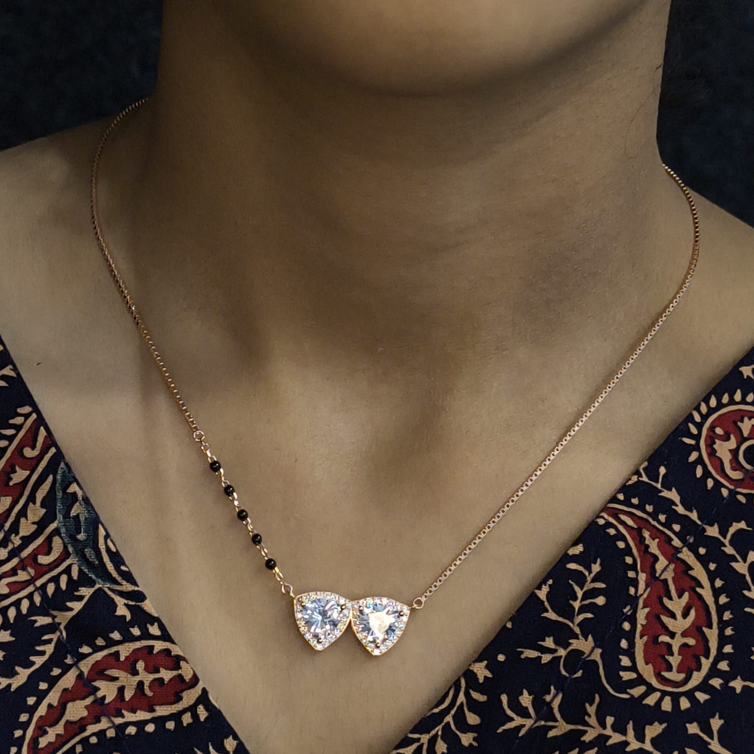 Necklace with a heart-shaped pendant on a person wearing a patterned garment.