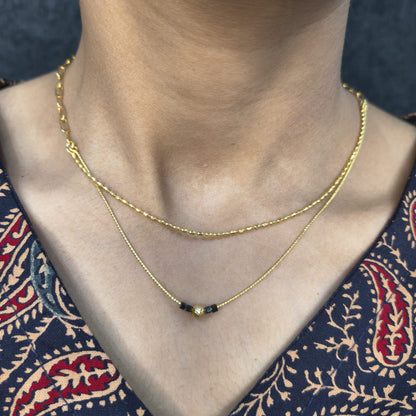 Gold necklace with a heart pendant on a person wearing a patterned garment.
