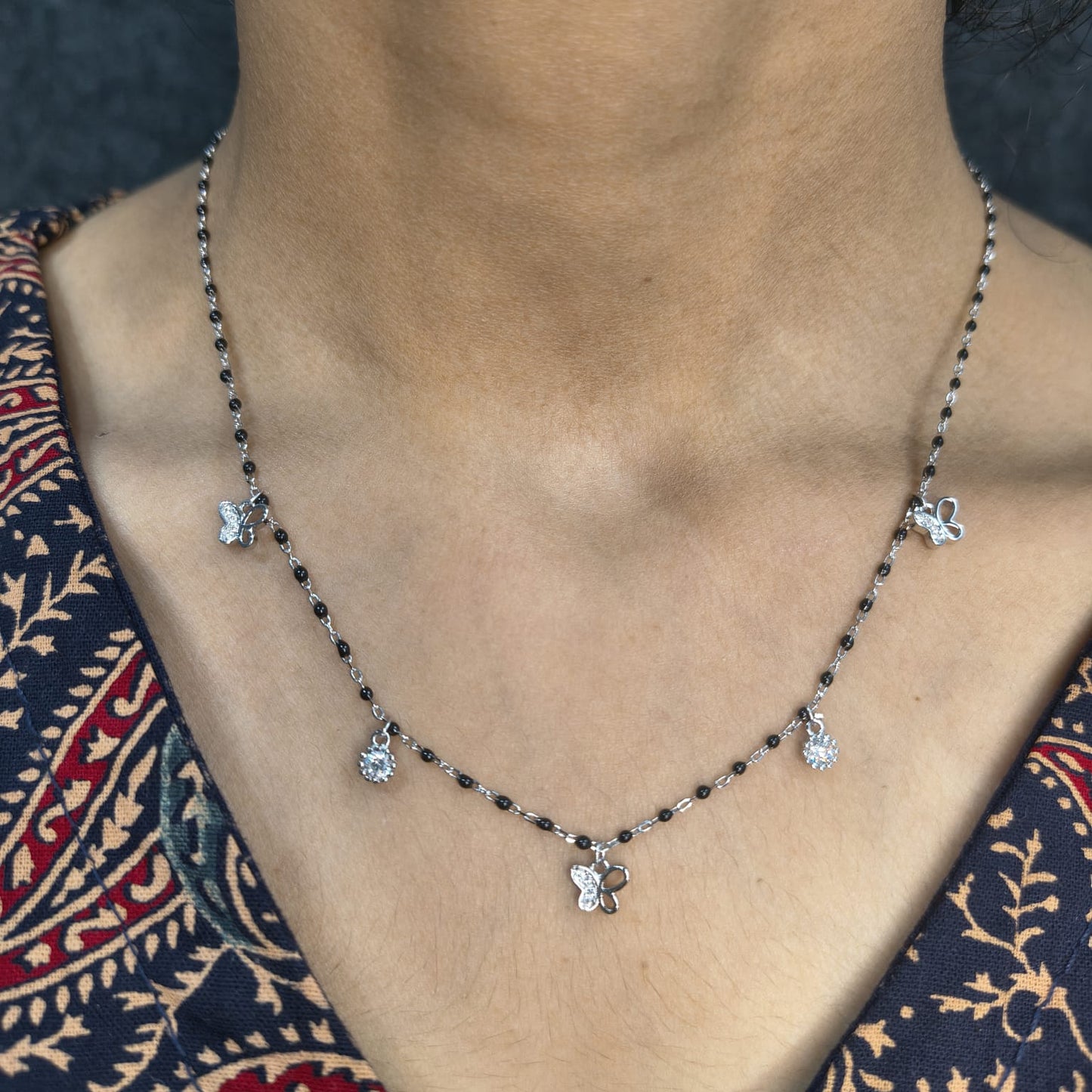 Necklace with floral pendants on a person wearing a patterned garment