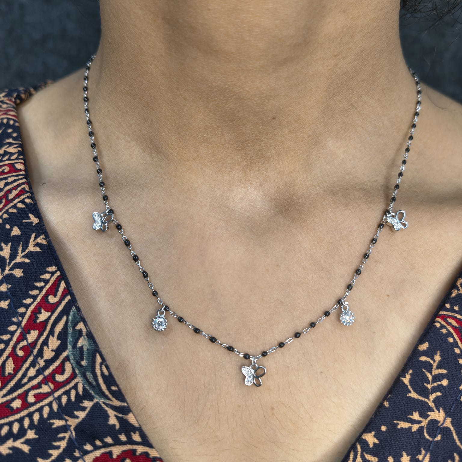 Necklace with floral pendants on a person wearing a patterned garment