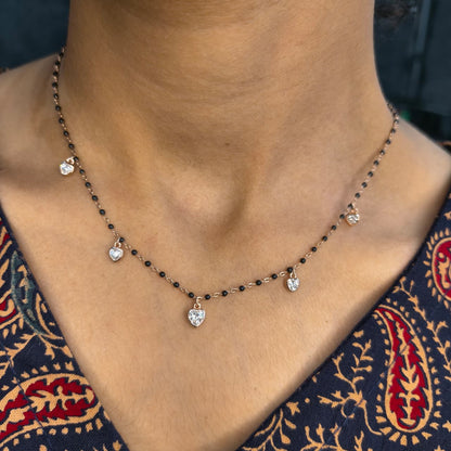 Necklace with heart-shaped pendants on a person wearing a patterned garment