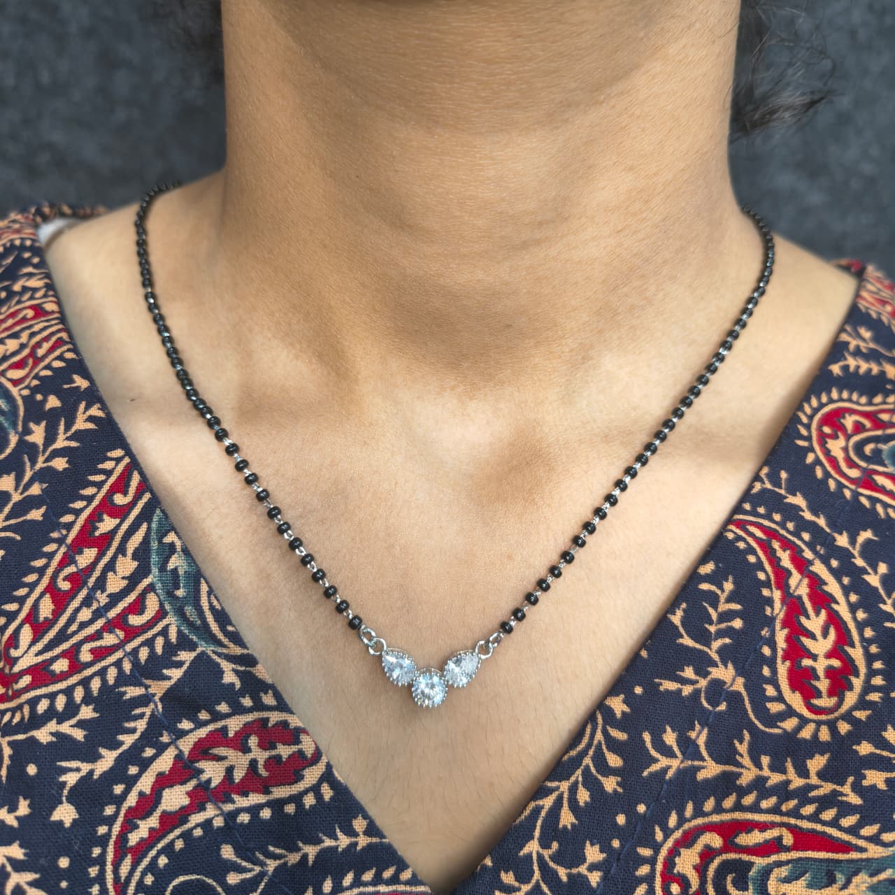 Necklace with a pendant worn by a person in a patterned garment