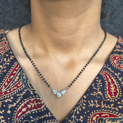 Necklace with a pendant worn by a person in a patterned garment