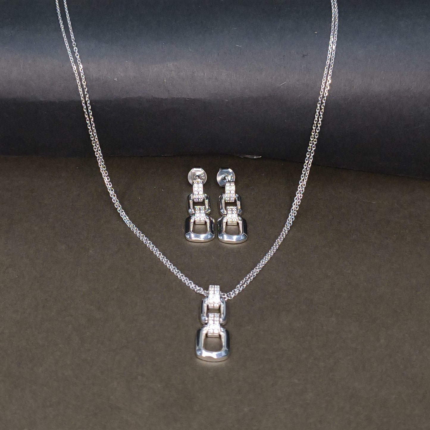 Silver necklace and earrings set on a dark background