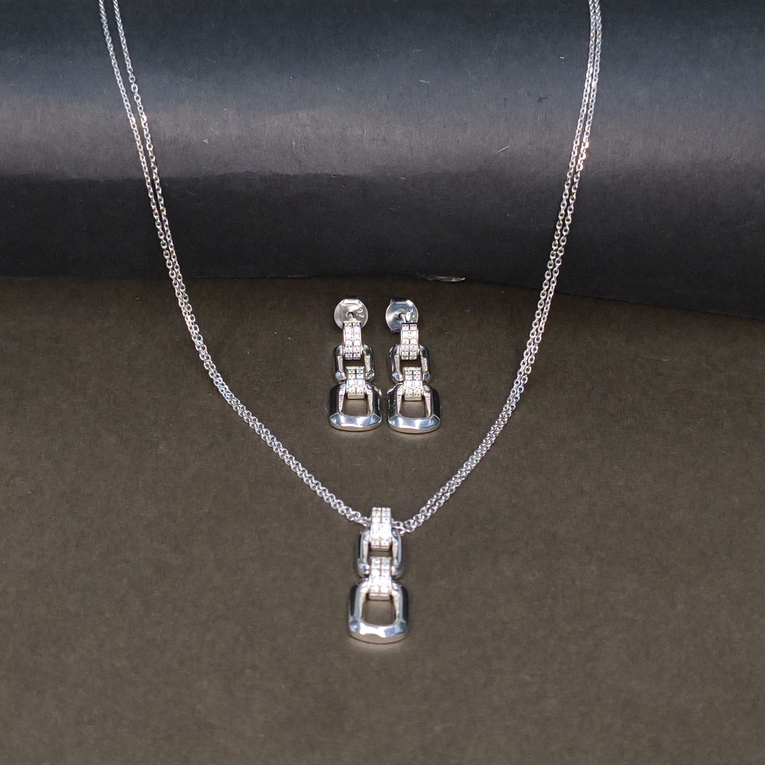 Silver necklace and earrings set on a dark background