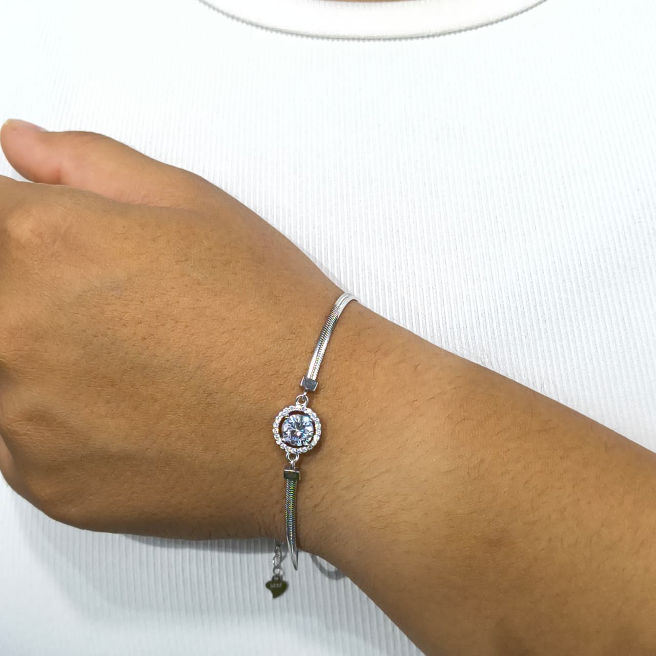 Silver bracelet with a blue gemstone on a wrist against a white background