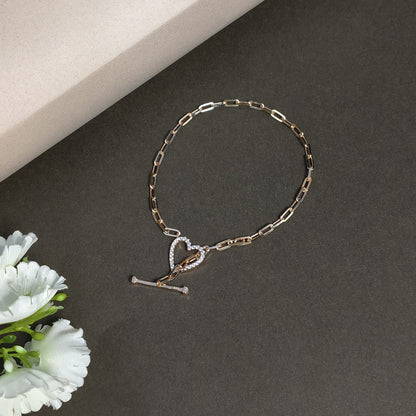 Bracelet with heart and key charm on a dark surface with white flowers