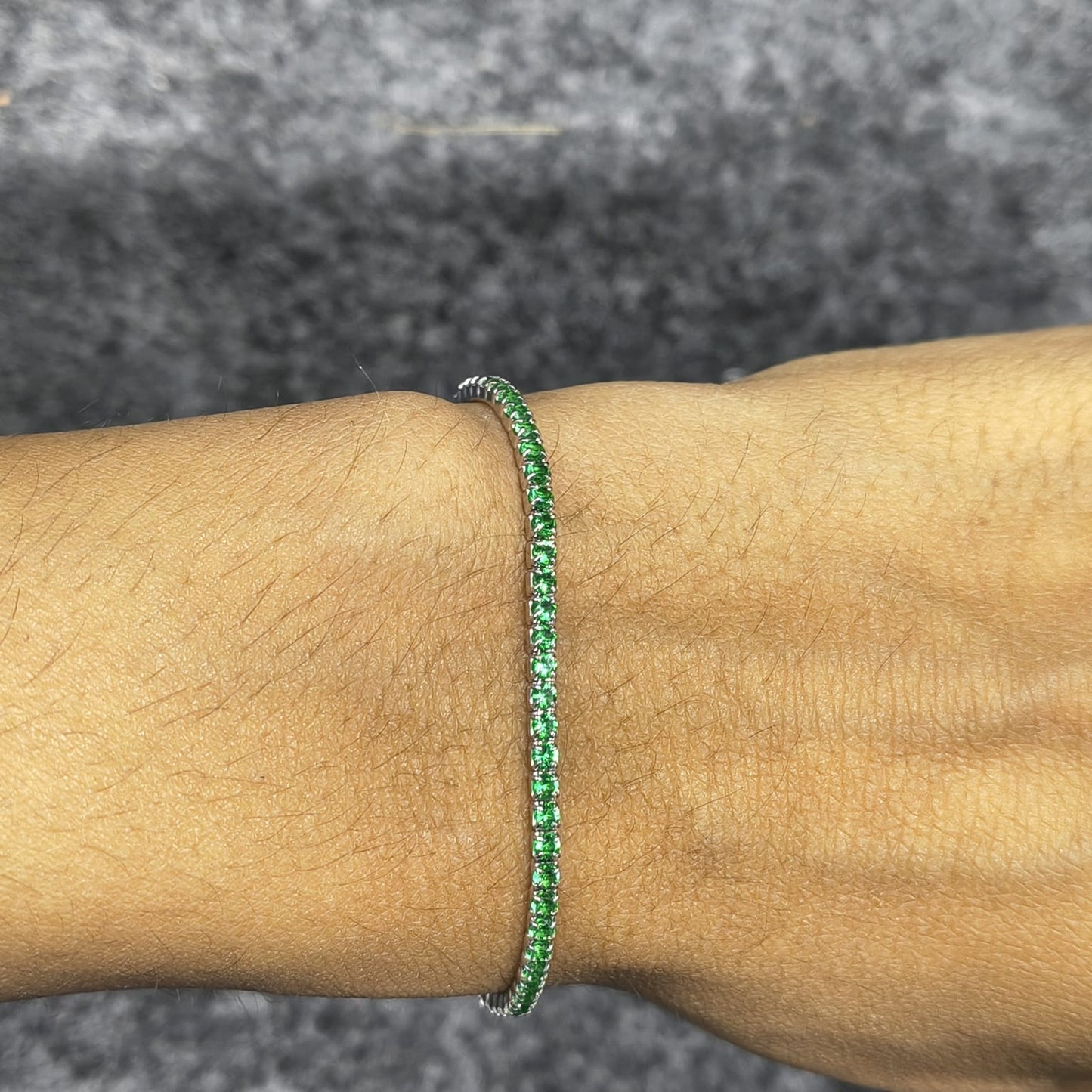 Green bracelet on a wrist with a gray textured background