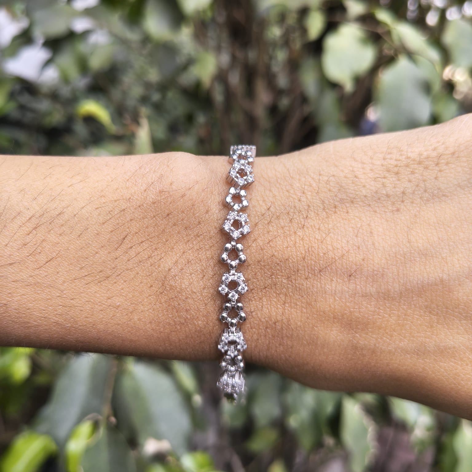 Silver bracelet on a wrist with a blurred green background