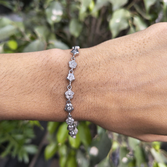 Silver bracelet on a wrist with a green leafy background