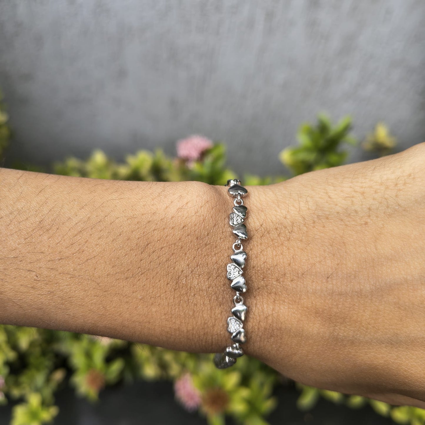 Silver bracelet on a wrist with a blurred natural background