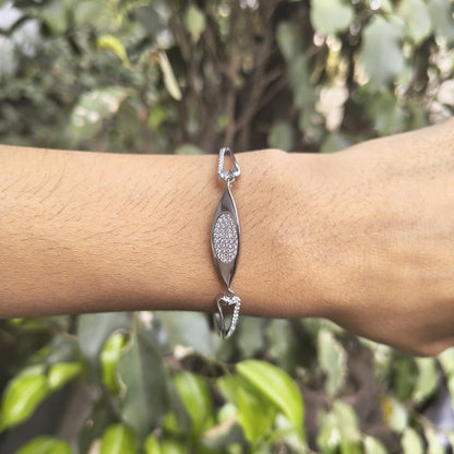 Silver bracelet with a diamond-like stone on a wrist against a blurred green background