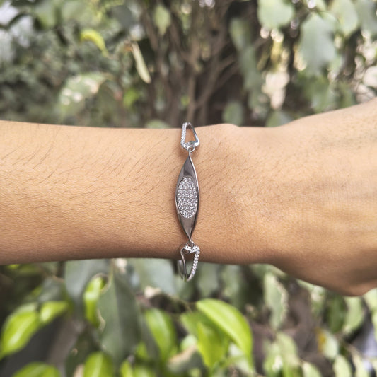 Silver bracelet with a diamond-like stone on a wrist against a blurred green background