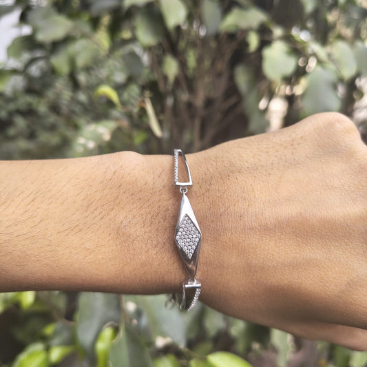 Silver bracelet on a wrist with a blurred green background