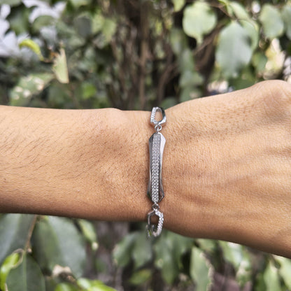 Silver bracelet on a wrist with a blurred green leafy background