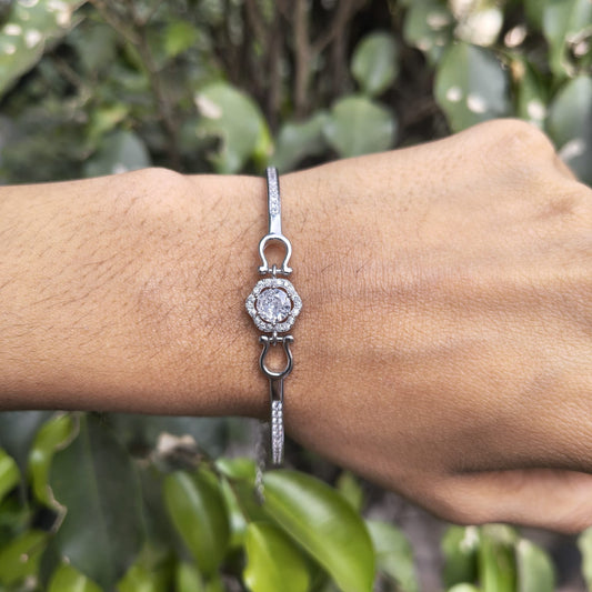 Silver bracelet with a diamond on a wrist against a green leafy background