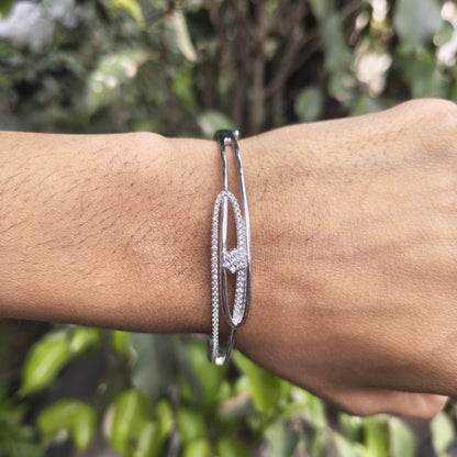 Silver bracelet on a wrist with a blurred green background