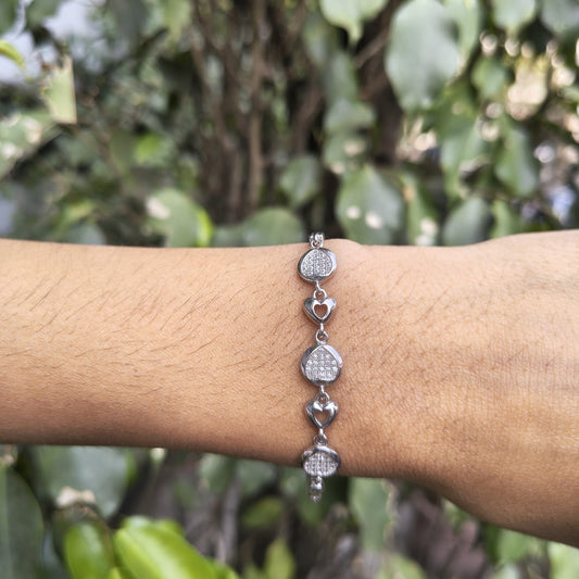 Silver bracelet on a wrist with a blurred green leafy background