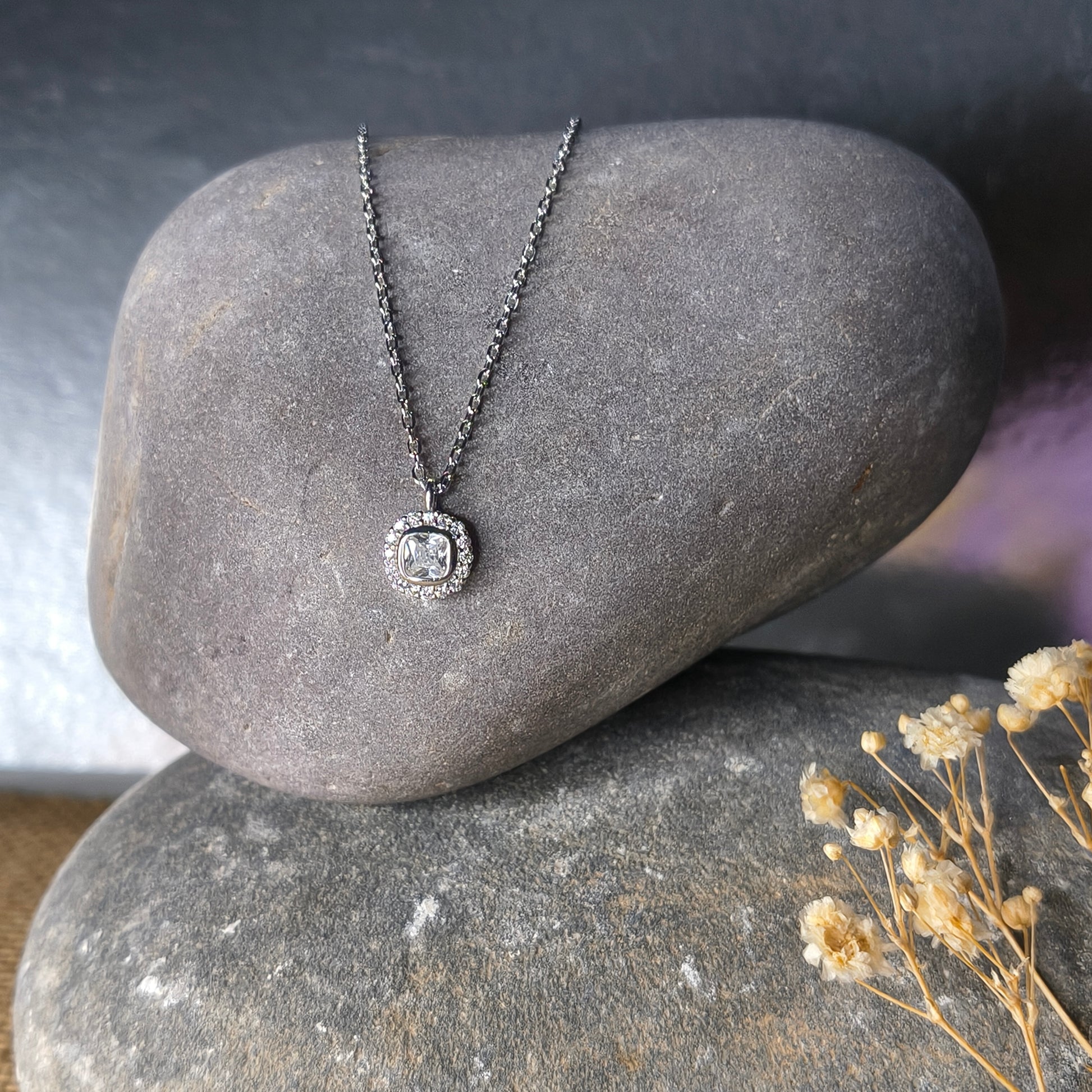 Silver necklace with a pendant on a stone surface