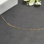 Gold necklace on a dark surface with a white flower