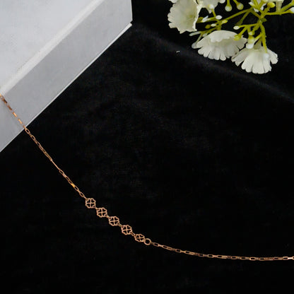 Rose gold chain on a black surface with white flowers in the background